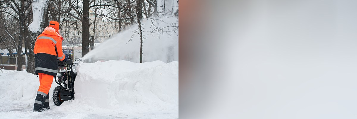 Worker using a snow blower outdoors