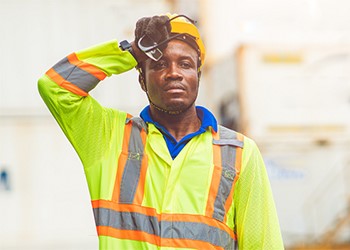 Worker in high-vis jacket wiping forehead