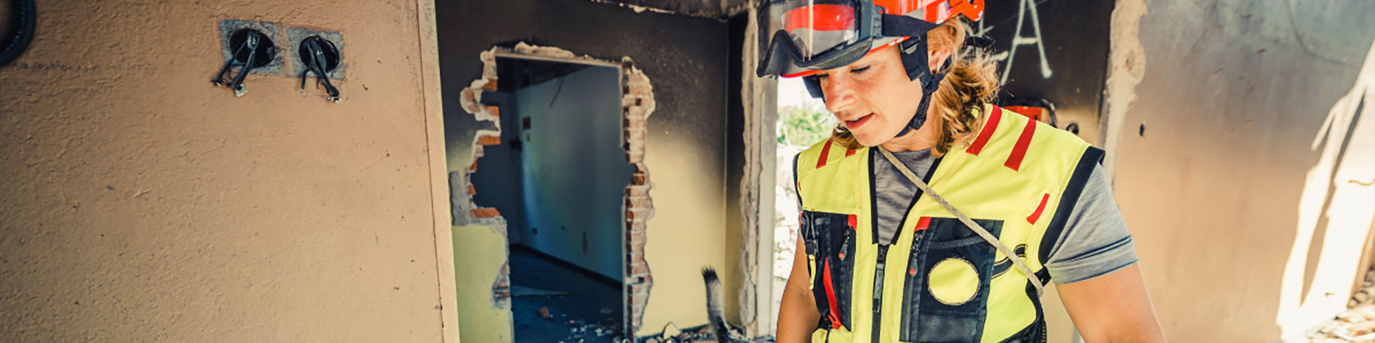 Emergency preparedness helper walking through burnt building aftermath