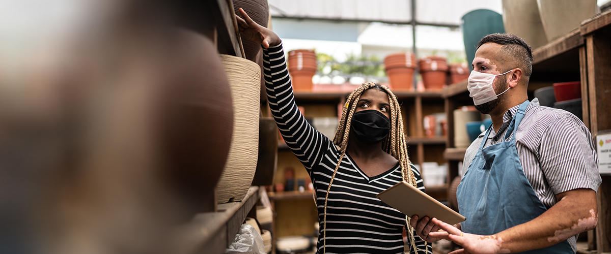Salesman helping client shopping for plant vase in a garden center | Photo Credit: iStock/FG Trade