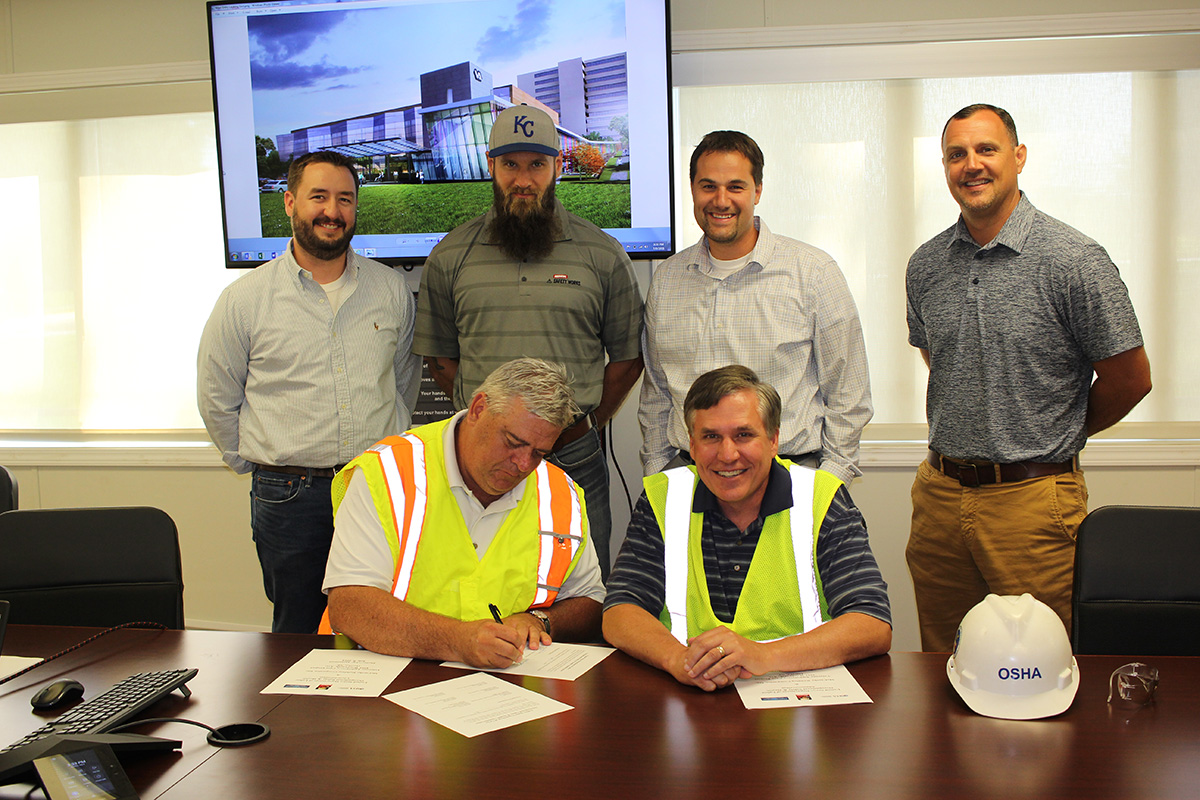 back row left to right): Kris Montgomery, Project Manager, McCarthy Construction Companies; Andy Parrish, Assistant Project Safety Manager, McCarthy Construction Companies; Ryan Sawall, Project Director, McCarthy Construction Companies; Steve Miller, Divisional Safety Director, McCarthy Construction Companies. (front row left to right): Darwin Craig, Assistant Area Director, Omaha Area Office, US DOL-OSHA, signing the agreement and Jeff Funke, Area Director, Omaha Area Office, US DOL-OSHA.