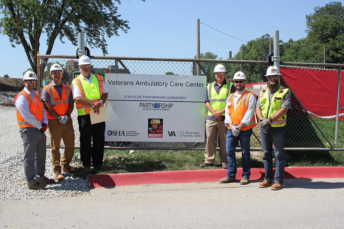 (standing left to right): Ryan Sawall, Project Director, McCarthy Construction Companies; Steve Miller, Divisional Safety Director, McCarthy Construction Companies, Darwin Craig, Assistant Area Director, Omaha Area Office, US DOL-OSHA, Jeff Funke, Area Director, Omaha Area Office, US DOL-OSHA, Kris Montgomery, Project Manager, McCarthy Construction Companies; and Andy Parrish, Assistant Project Safety Manager, McCarthy Construction Companies after the signing ceremony.