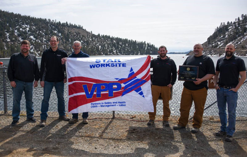 Six Hauser Plant employees hold a VPP Star flag.