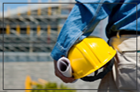 photo of worker with hard hat looking at a building in the distance