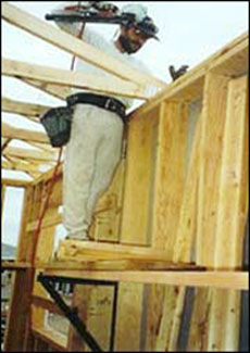 Figure 1 - A worker installing roof trusses from an interior bracket scaffold. For problems with accessibility in using figures and illustrations, please contact the DOC at 202-693-2020.