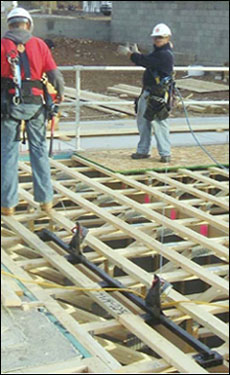 Figure 20 - Workers using a truss bracket anchor while installing a subfloor. For problems with accessibility in using figures and illustrations, please contact the DOC at 202-693-2020.