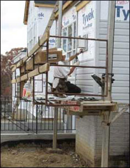 Figure 32 - A worker performing siding activities from a pump jack scaffold. For problems with accessibility in using figures and illustrations, please contact the DOC at 202-693-2020.