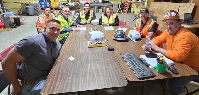 Seated at a conference table, OSHA staff, with representatives from Langley & Associates and the Montana Department of Labor and Industry Consultation Program, sign the Partnership agreement.  