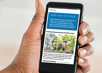 Photograph of hand holding a phone showing OSHA Training page