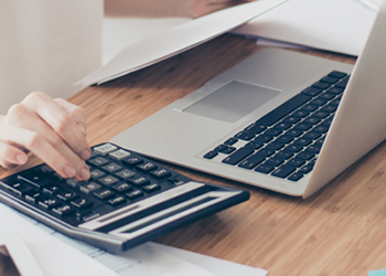 Worker using laptop and calculator