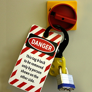 Photograph showing a lockout/tagout system, with a card reading: DANGER - This tag & lock to be removed only by person shown on the other side.