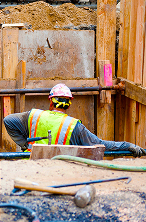 Workers in high-viz vests and hardhats, working on a trench site