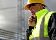 Worker in hard hat and high-visibility vest on phone