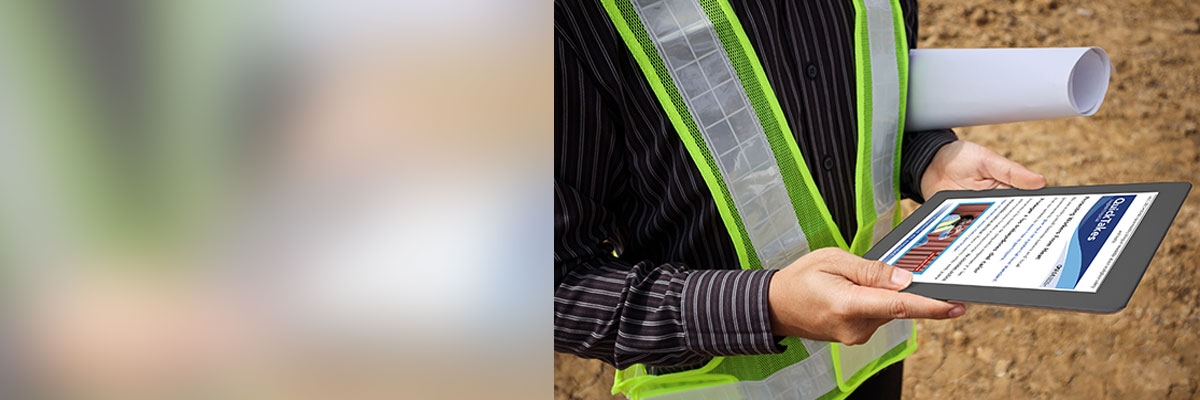 Person in yellow construction vest holding a tablet showing a QuickTakes newsletter